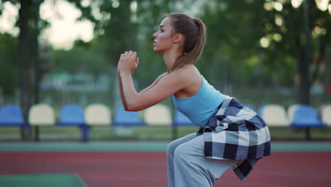 close up beautiful sportswoman doing squats in sport playground outdoor.