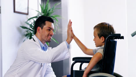 el doctor le da cinco a un niño discapacitado.