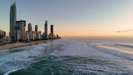 aerial view of gold coast at sunrise with waves gently rolling onto the beach, highlighting the city's skyline
