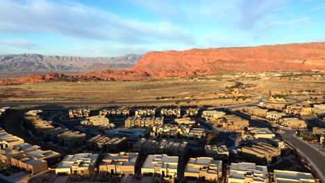 flying over the development of houses and passing cars on the road in the desert and mountains at sunset