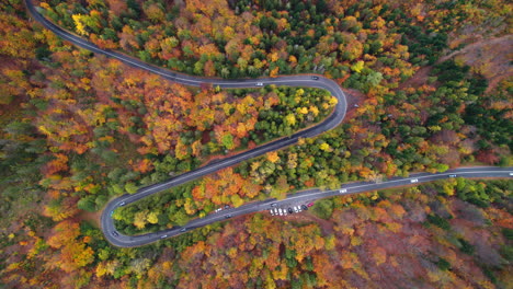 Winding-mountain-road-trough-the-forest-in-the-autumn-with-cars-passing-on-the-road