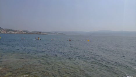 People-in-a-group-taking-paddle-surf-lessons-on-a-sunny-day-at-dawn-on-the-coast-with-the-Trnaquilo-Sea