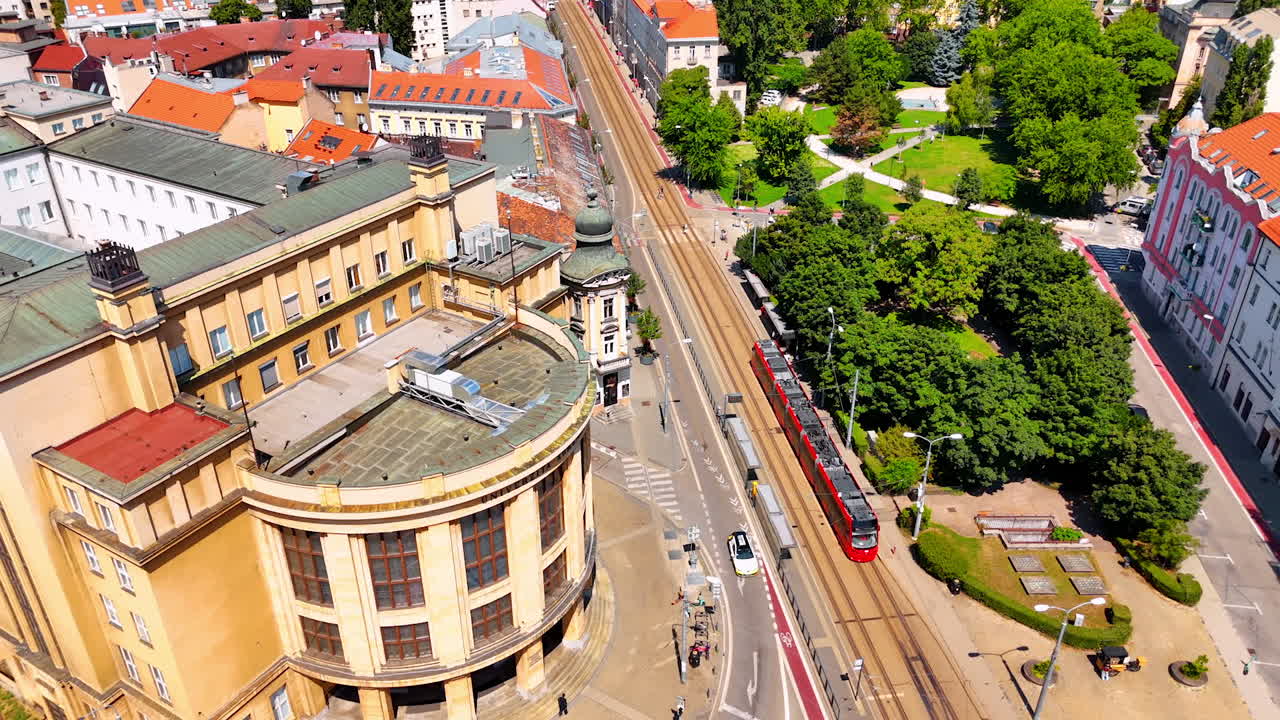 Following the tram moving by the road in the city center of Bratislava, Slovakia. Drone footage over the sunny cityscape.