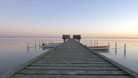 camera moves along wooden pier with attached boats