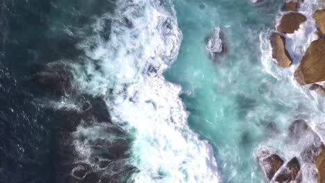 top down bird eye view of strong and danger ocean waves crashing on to the rocks
