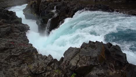 spectacular blue colored waterfall crashing down edge in slow motion in iceland