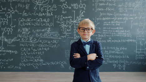 young boy in formal attire in front of a blackboard filled with equations