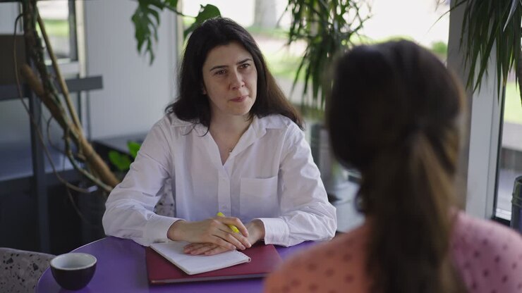 Portrait of curios HR manager listening applicant sitting in cozy cafe indoors. Caucasian woman interviewing employee in coffee house smiling. Employment and lifestyle concept