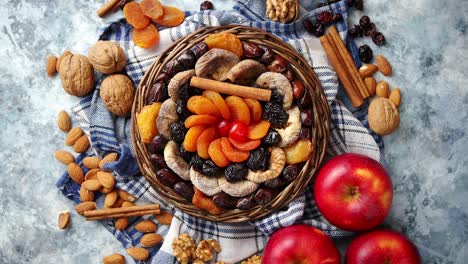 Composition-of-dried-fruits-and-nuts-in-small-wicker-bowl-placed-on-stone-table