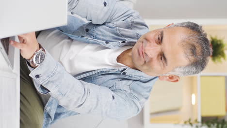 Vertical-video-of-Man-looking-at-laptop-making-positive-gesture.