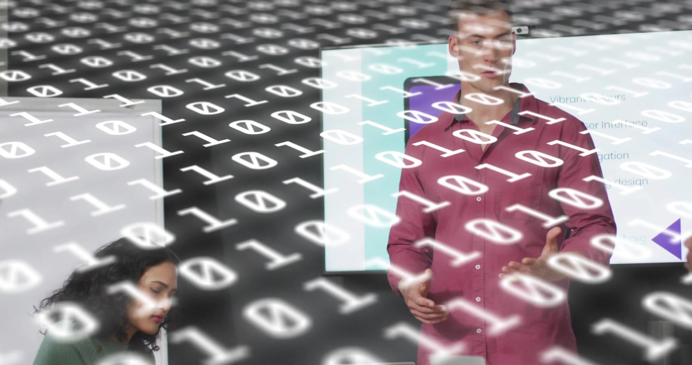 Presenter clicking remote and presenting tech slide while teammate typing under binary data overlay