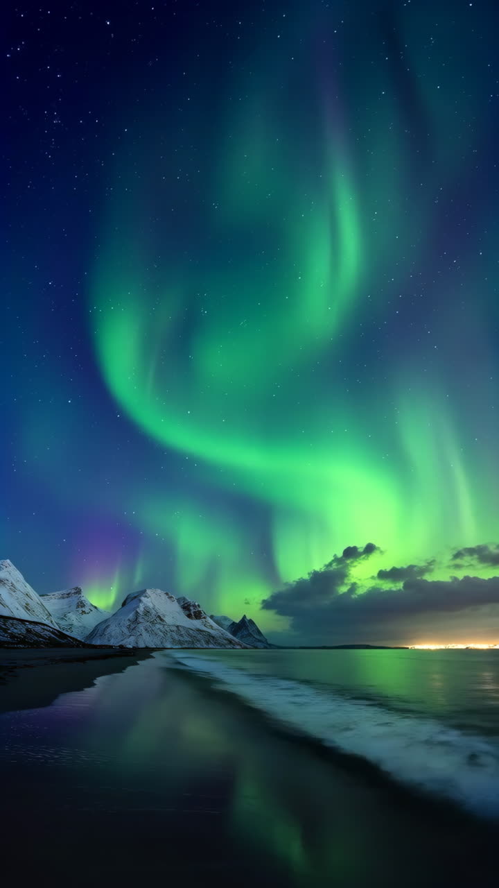 Vibrant Aurora Borealis Illuminates a Coastal Landscape with Snow-Capped Mountains