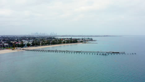 aerial over altona beach and pier with melbourne city skyline