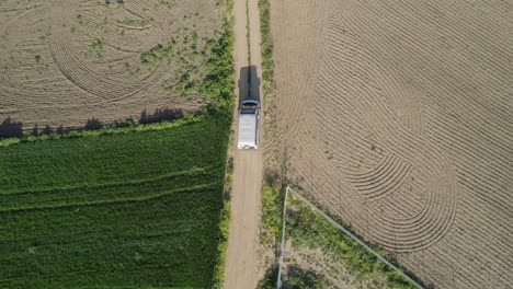 tracking aerial view looking down on a camper van on an unpaved road in southern spain in summer