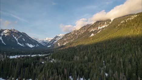 Clouds-boil-along-a-mountain-ridge-lit-by-the-golden-light-of-a-setting-sun,-aerial-hyperlapse