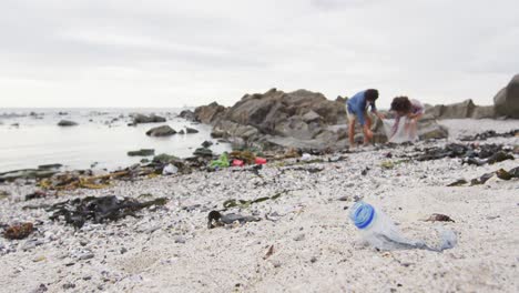 african american couple collecting garbage in a plastic bag at the beach