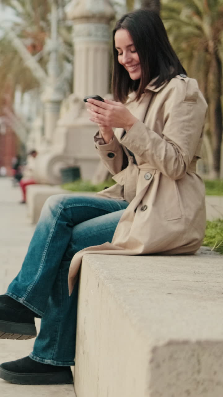 Giovane donna sorridente che scrive messaggi sullo smartphone all'aperto
