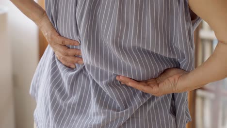 close up of old woman hands grabing on hurt lower back