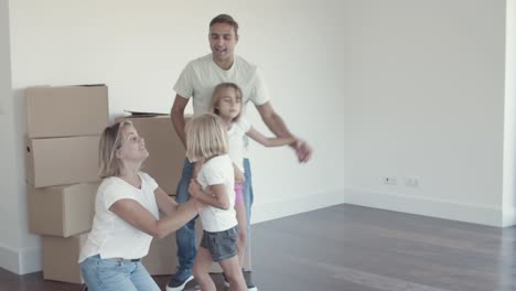 Padres-Alegres-Y-Dos-Niñas-Bailando-En-Su-Nuevo-Apartamento