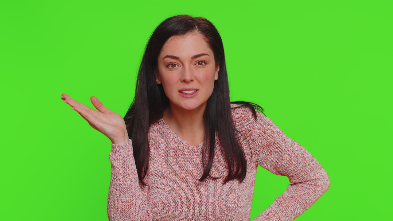 mujer joven tratando de oírte, mirando confundido y fruncido, manteniendo el brazo cerca de la oreja para una voz más alta