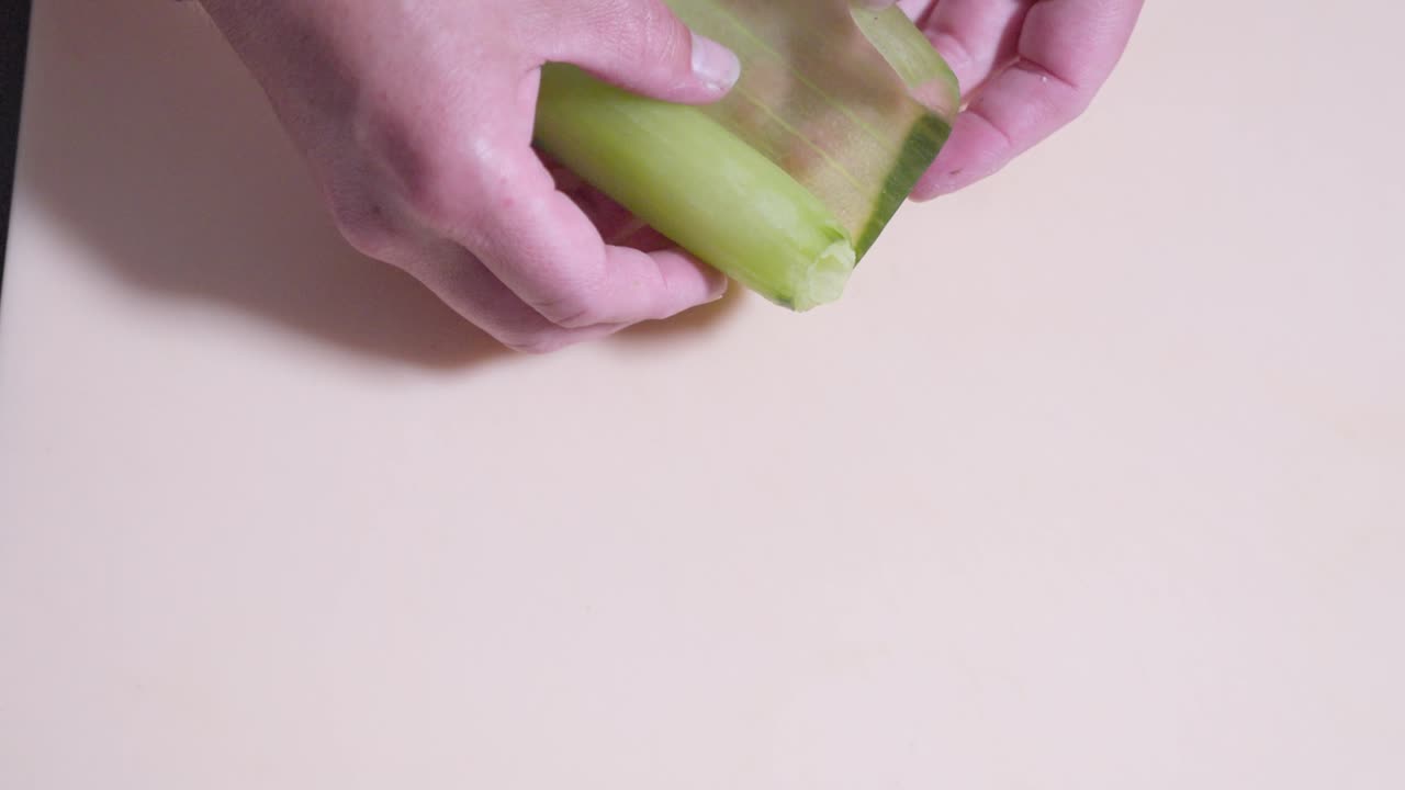 A static overhead shot of thinly sliced cucumber being unrolled, showcasing the sushi preparation process. Perfect for highlighting fresh ingredients and the art of making sushi rolls.
