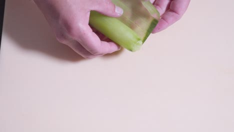 a static overhead shot of thinly sliced cucumber being unrolled, showcasing the sushi preparation process. perfect for highlighting fresh ingredients and the art of making sushi rolls.