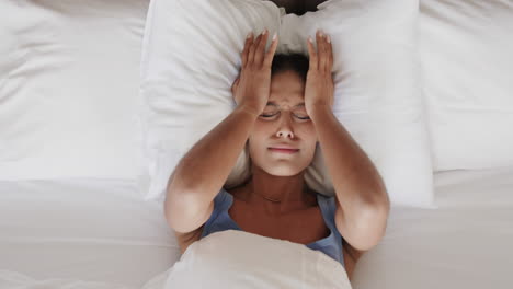 tired biracial woman lying in bed at home, slow motion