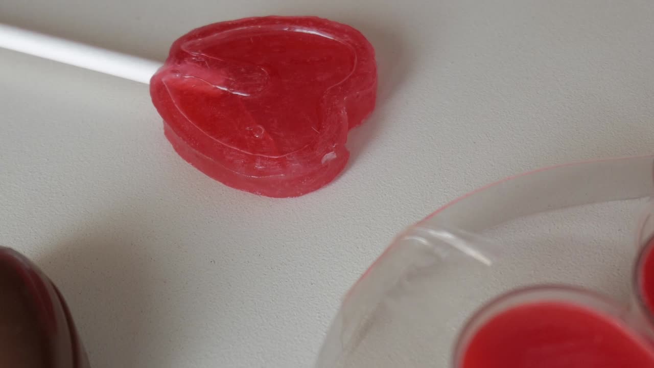 Heart-shaped lollipop for Valentine's Day celebration, red candy on a white table