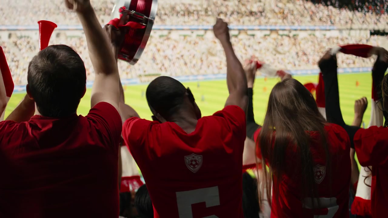Vista trasera de aficionados deportivos de varias generaciones en la sección de hinchas.