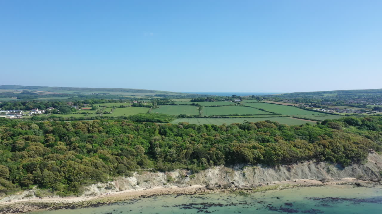 Vista aerea di un paesaggio costiero con scogliere, foresta e campi verdi
