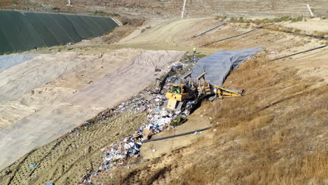 aerial view of a landfill with heavy machinery compacting waste