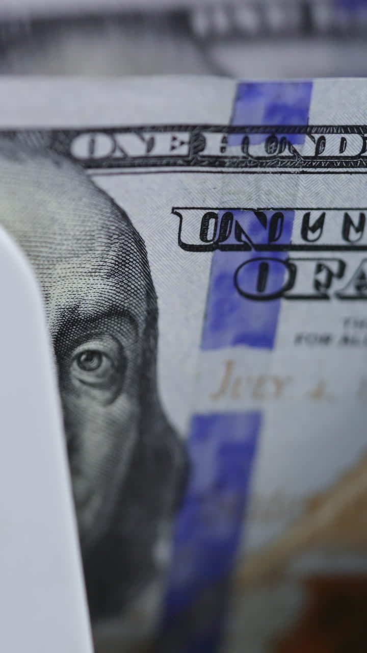 Cash money counting machine. Banknote counter are counting one hundred dollar bills. Macro shot. Vertical video