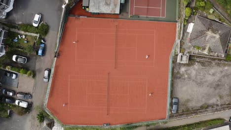 canchas de tenis rojas con pares de jugadores atléticos jugando durante un partido