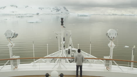 a person standin on the bow of the ship in winter time