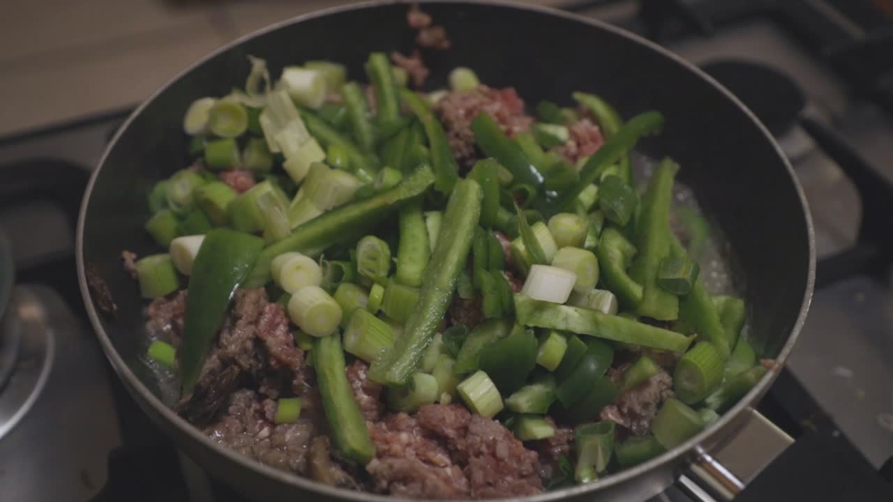carne picada con cebollas de primavera cocinadas en una sartén
