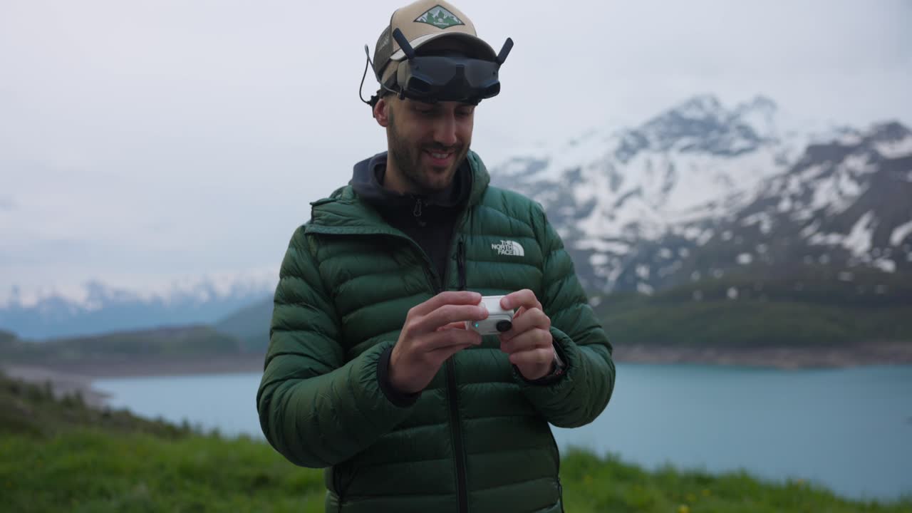 Man preparing FPV drone equipment in a mountain lake landscape