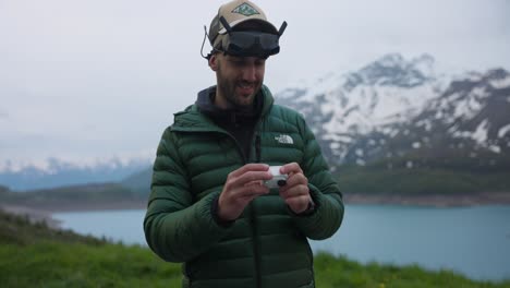 man preparing fpv drone equipment in a mountain lake landscape