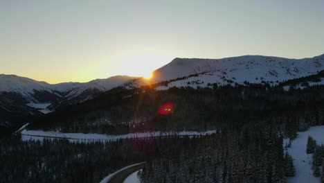 Aerial-of-sun-just-peaking-over-side-of-mountain-in-Berthound-pass