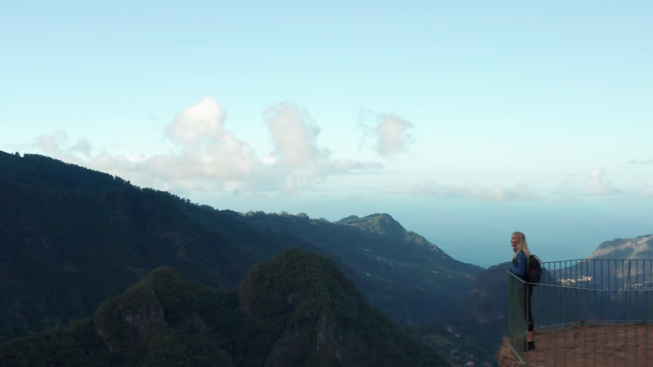 여자는 숨막히는 경치를 즐기기 위해 탁 트인 플랫폼 끝까지 걸어갑니다.