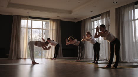 Jóvenes-Deportistas-Caucásicos-Practicando-Clases-De-Yoga-Con-Instructor.-Grupo-Caucásico-De-Mujeres-Que-Ejercen-Un-Estilo-De-Vida-Saludable-En-El-Gimnasio.-Clase-De-Gimnasia-De-Actividad-Deportiva.-Camara-Lenta.