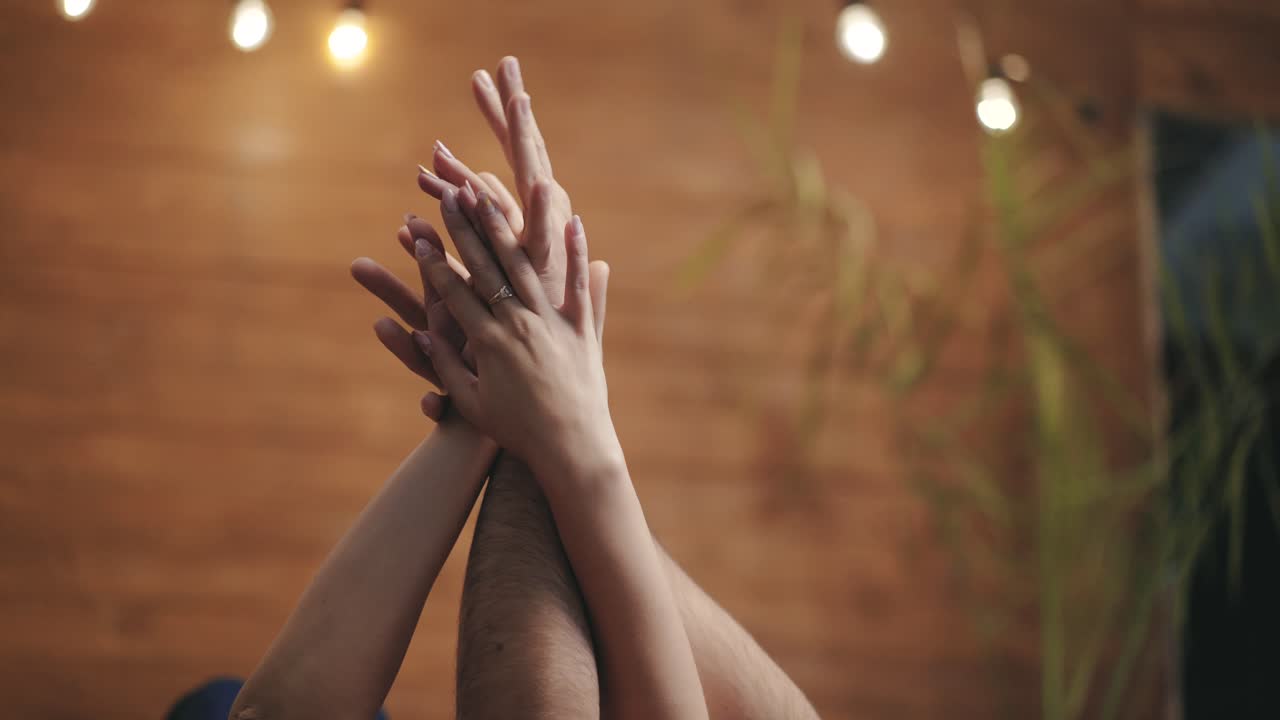 hands of funny enamored are interlacing and touching each other in the room on the background of wooden