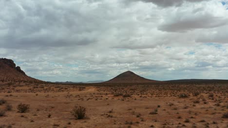 Low-altitude-flight-towards-a-volcanic-cone-shaped-mountain-in-the-Mojave-Desert---aerial-push-forward