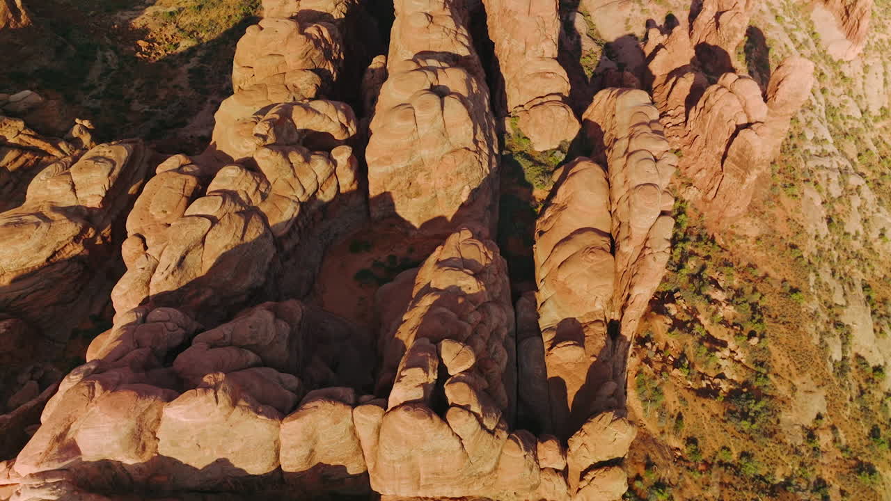 Group of rock formations with rounded tops from aerial erosion. Sunlit canyons of Arches National Park from top view.