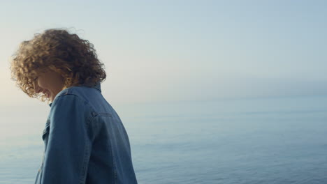 fashionable girl posing at seashore. smiling woman turning around on ocean beach