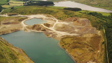 An-aerial-view-over-a-quarry-with-a-turquoise-pond