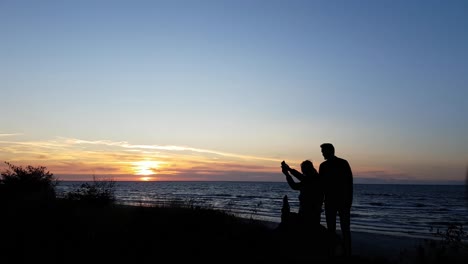 Pareja-Joven-Viendo-La-Puesta-De-Sol-En-La-Playa