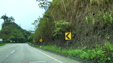 View-from-inside-the-car,-driving-through-a-curvy-road-between-hills-and-mountains-in-the-Andean-region-of-Ecuador