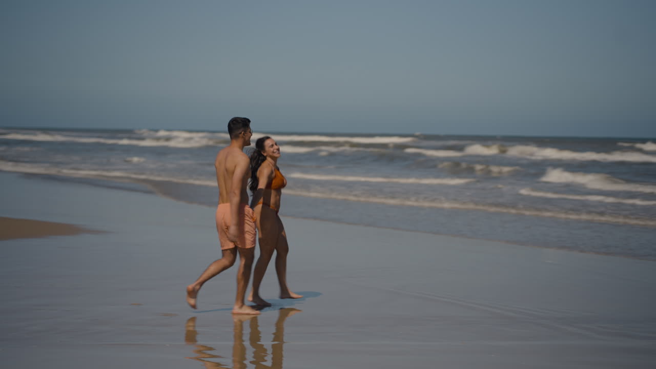 una pareja linda caminando hacia el mar.