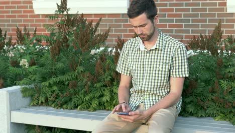 hombre usando un teléfono inteligente en un banco del parque