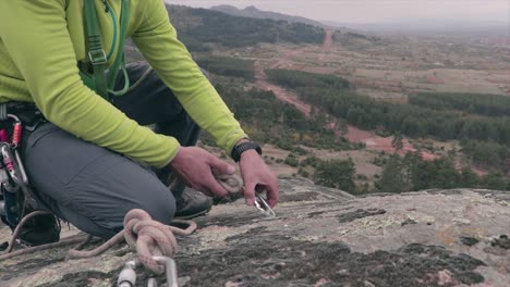 rock climber securing a rope on a carabiner on a rock